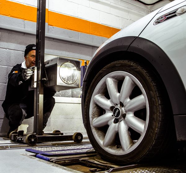 A vehicle technician performs a headlight beam test for an MOT at CCM Cranleigh